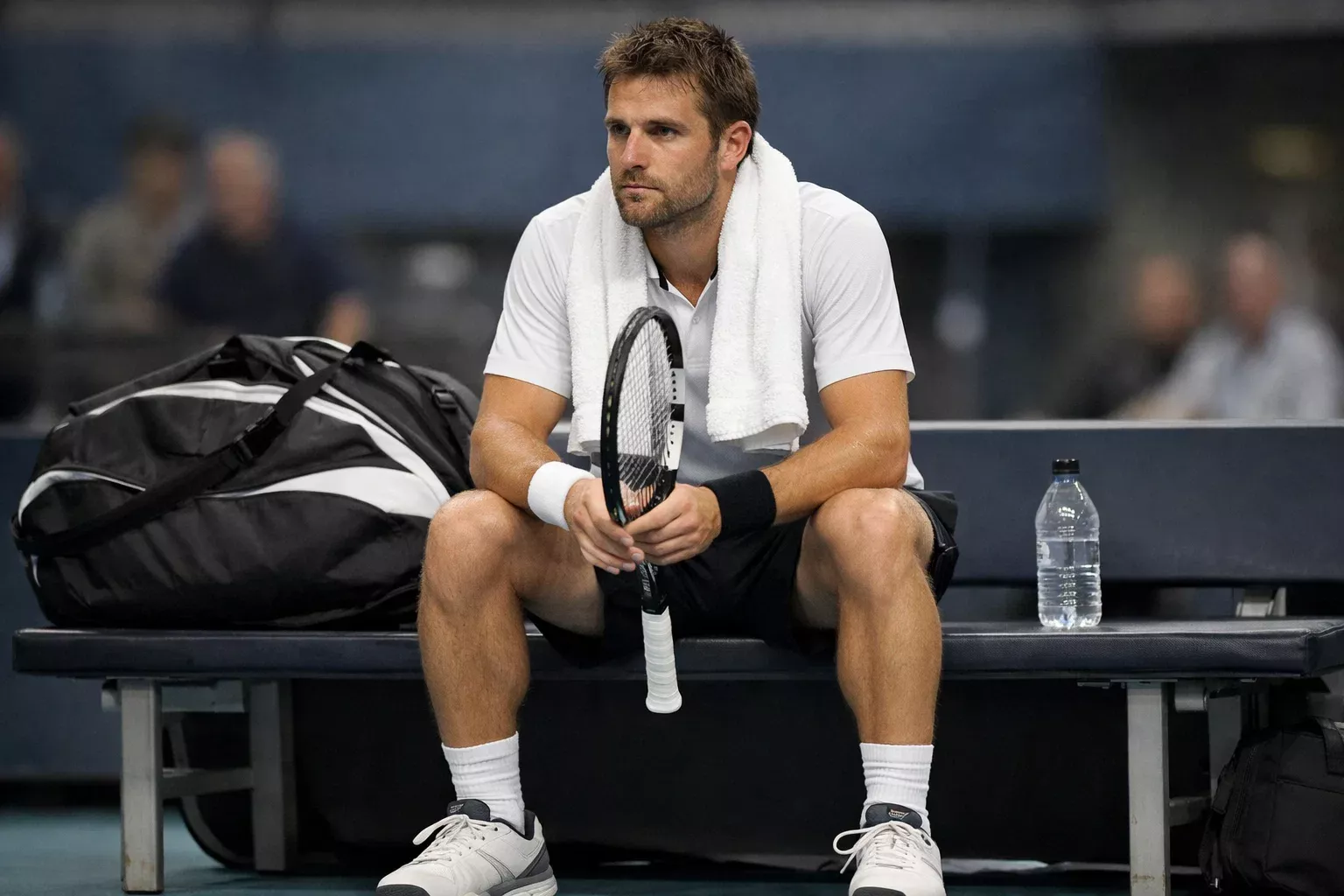 Tenista pensativo analizando su estrategia durante un descanso