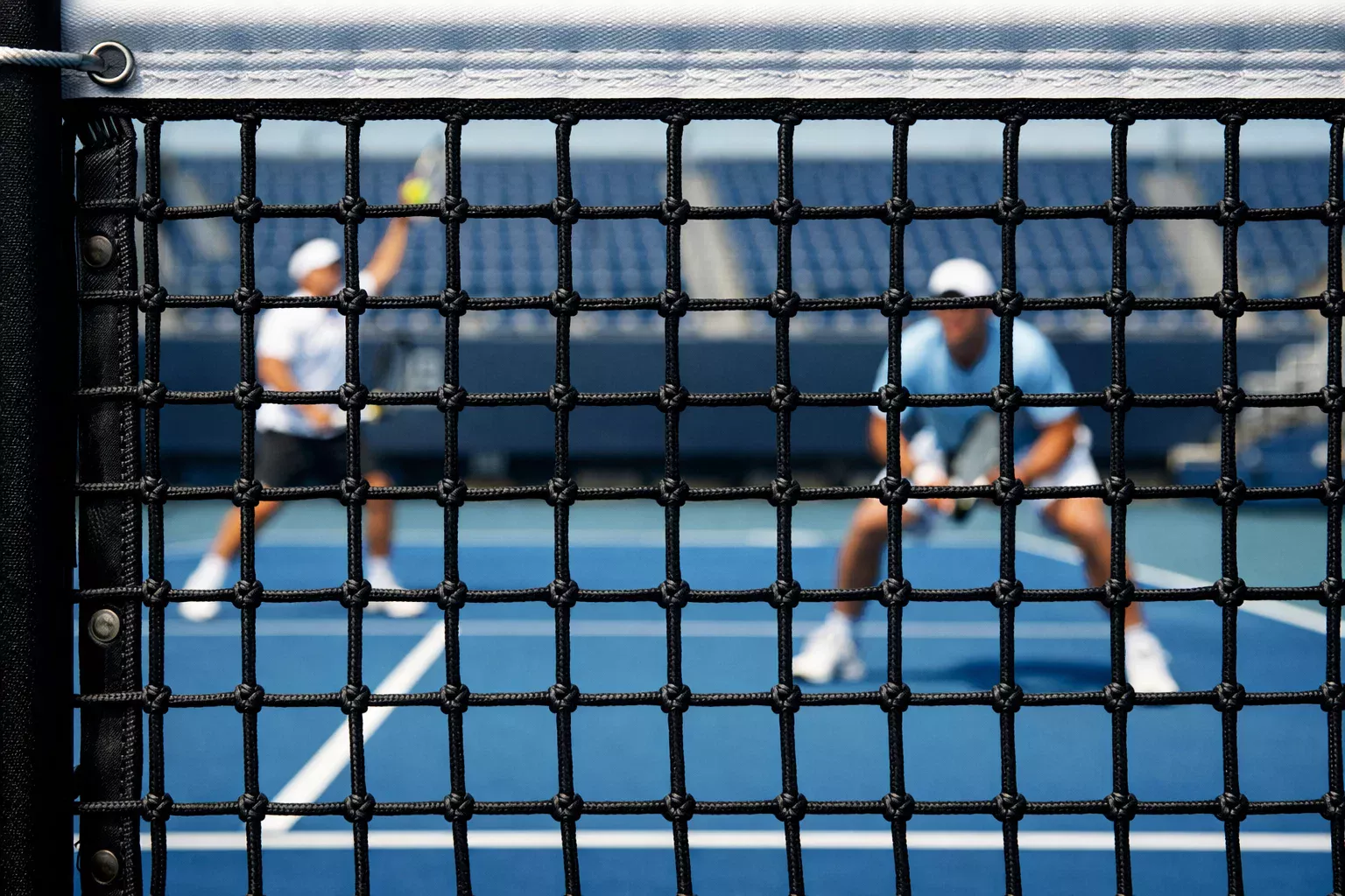 Vista de la red de tenis con jugadores preparados en el fondo